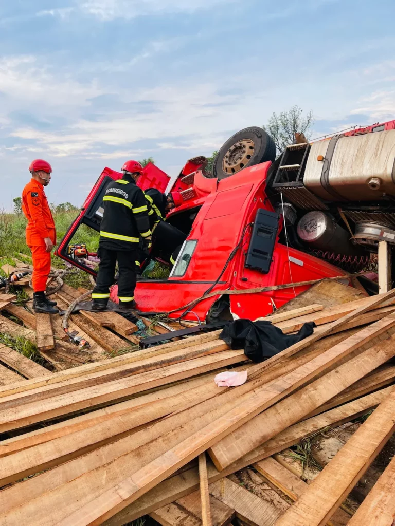 BOMBEIROS RETIRANDO MOTORISTA QUE MORREU APÓS FICAR PRESO EMBAIXO DE CARRETA DURANTE ACIDENTE