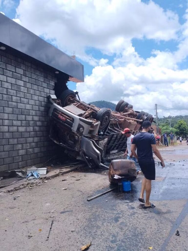 CAMINHÃO CARREGADO DE BOIS CAPOTA E ATINGE CASA ÀS MARGENS DE RODOVIA